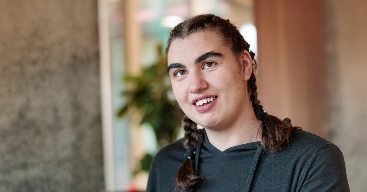 Portrait einer lachenden Frau mit Behinderung, die ein Stofftier in den Händen hält.