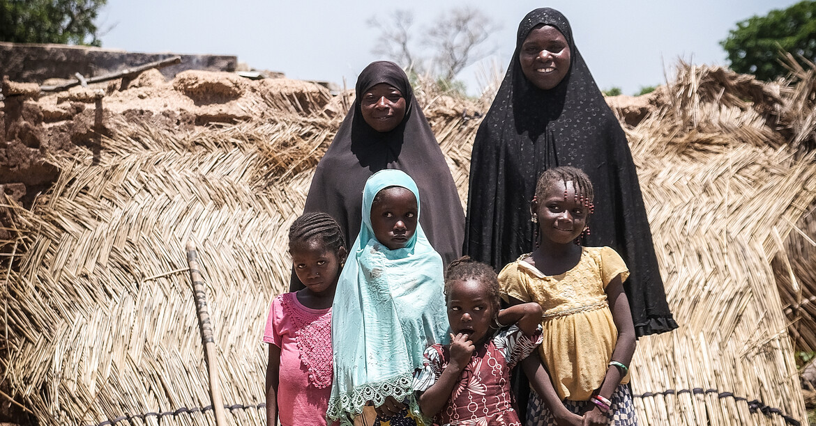 Eine Familie in Mali steht vor dem Dorf zu einem Gruppenfoto zusammen.